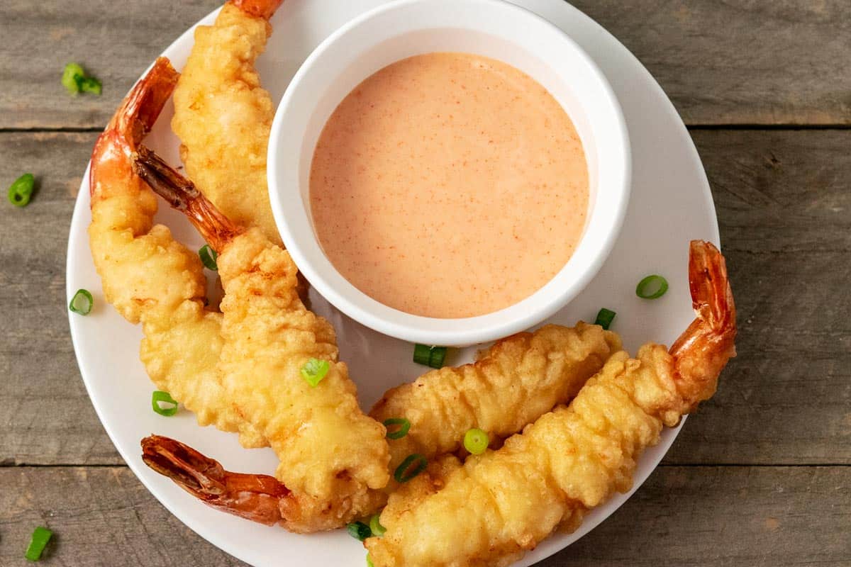 a bowl of hibachi yum yum sauce on a plate with shrimp tempura.