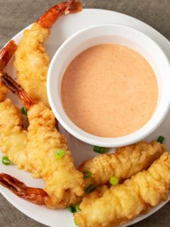 a bowl of homemade yum yum sauce on a plate with shrimp tempura.
