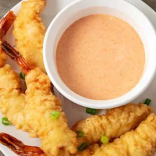 a bowl of homemade yum yum sauce on a plate with shrimp tempura.