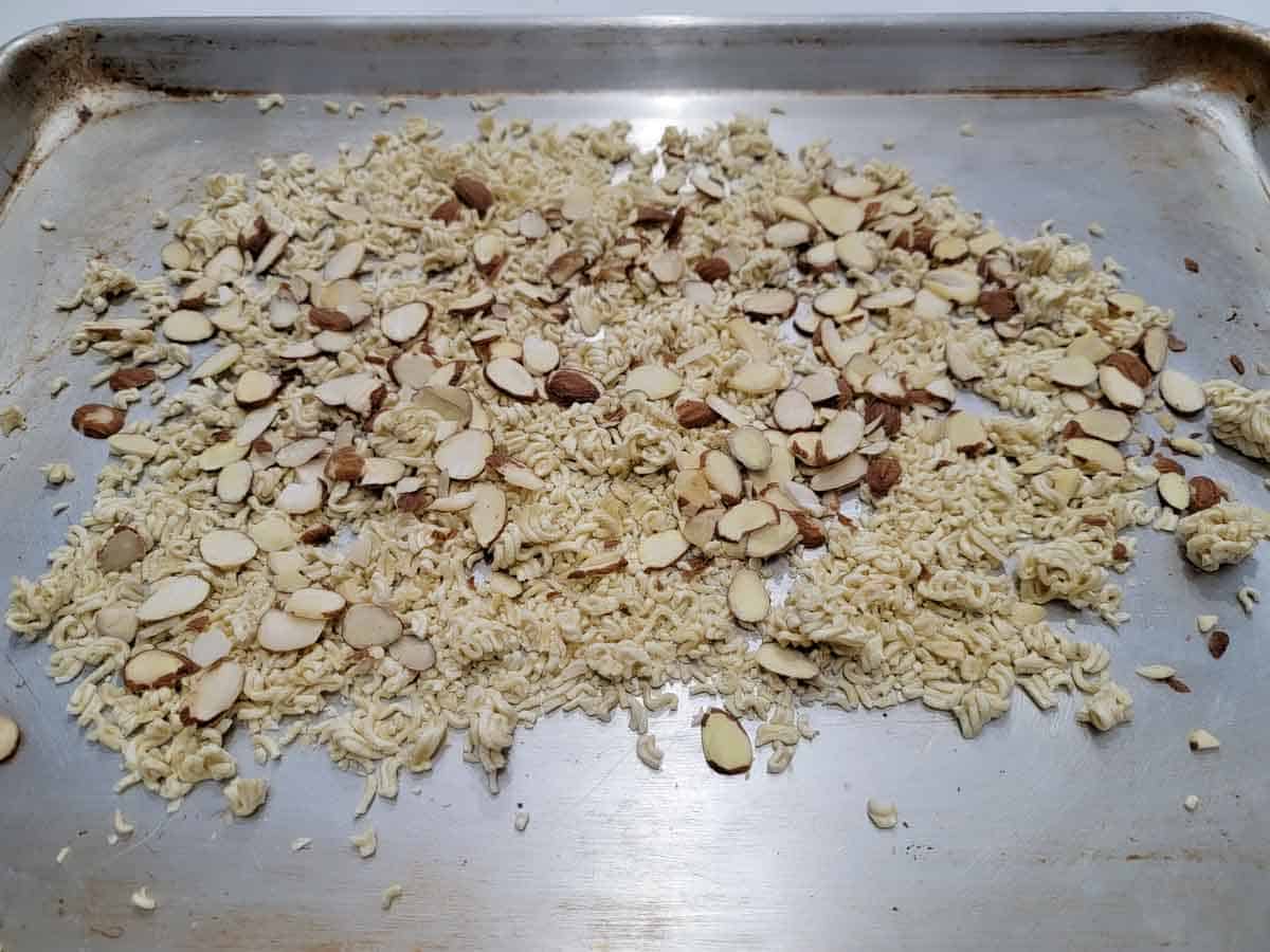 uncooked ramen and sliced almonds spread onto a baking sheet.
