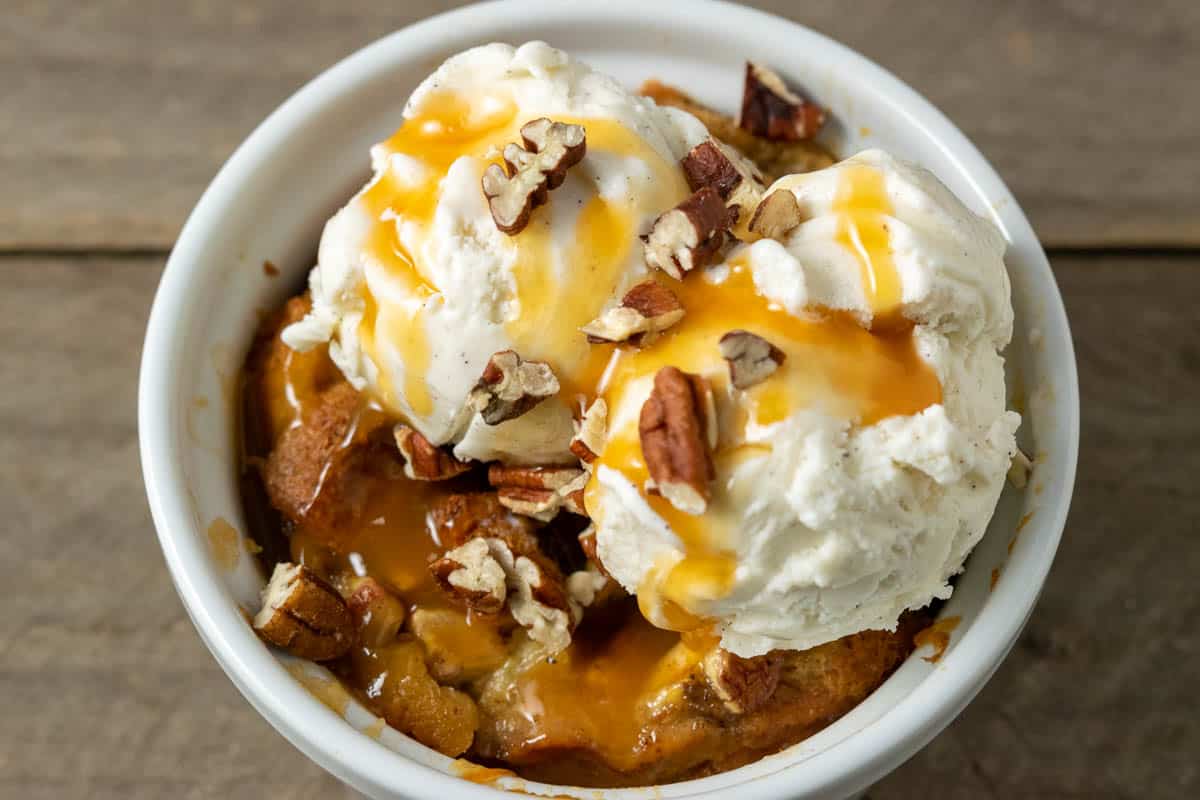 Pineapple Banana Bread Pudding topped with caramel sauce, pecans, and ice cream.