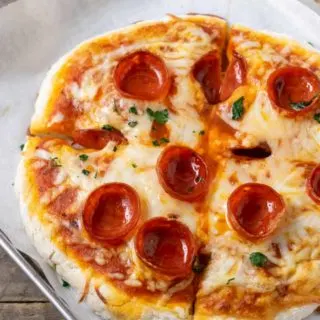 a small pepperoni pizza on a baking sheet.