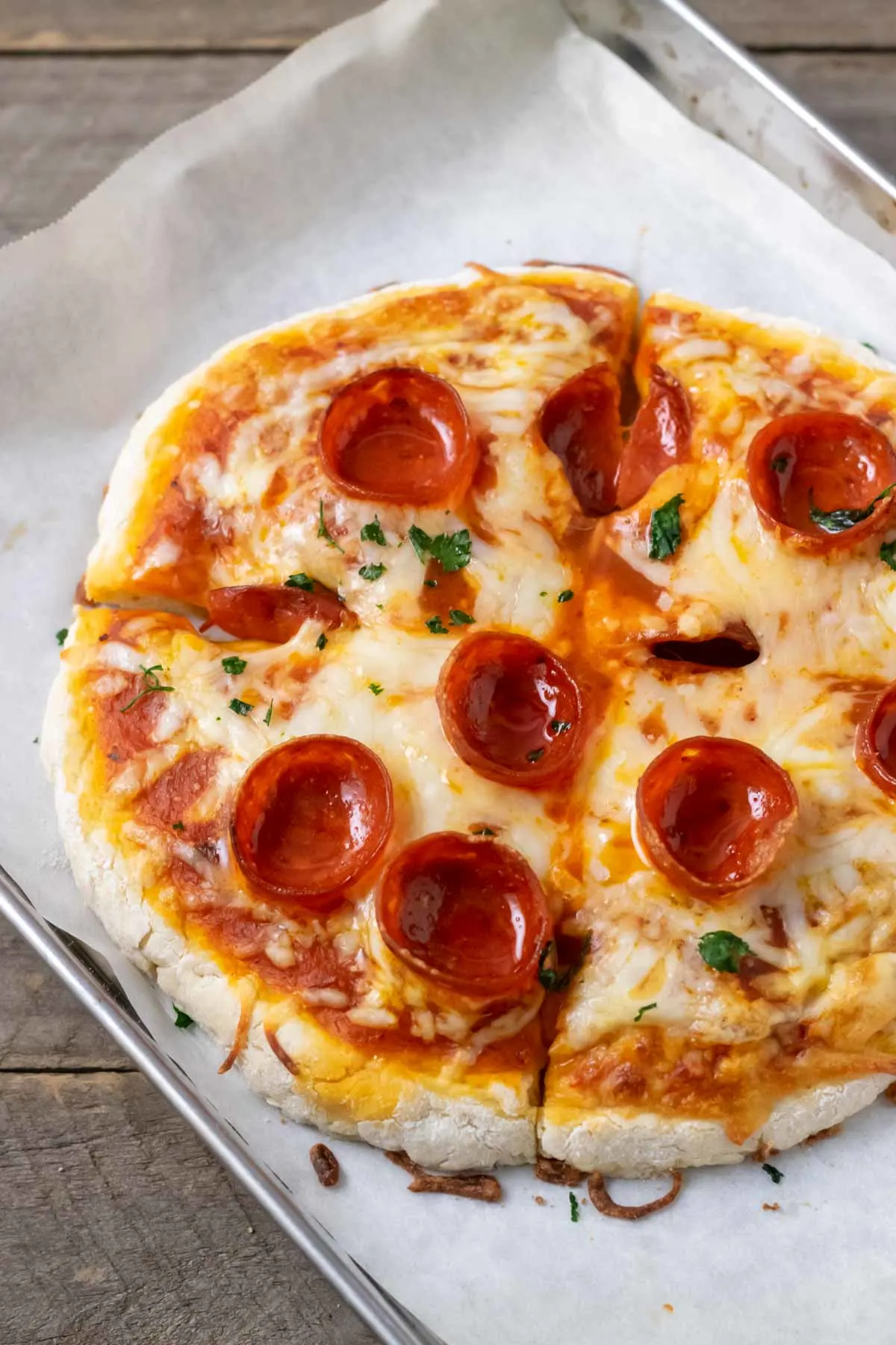 a small pepperoni pizza on a baking sheet.