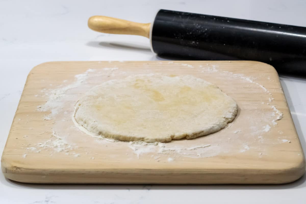 pizza dough rolled out onto a cutting board.