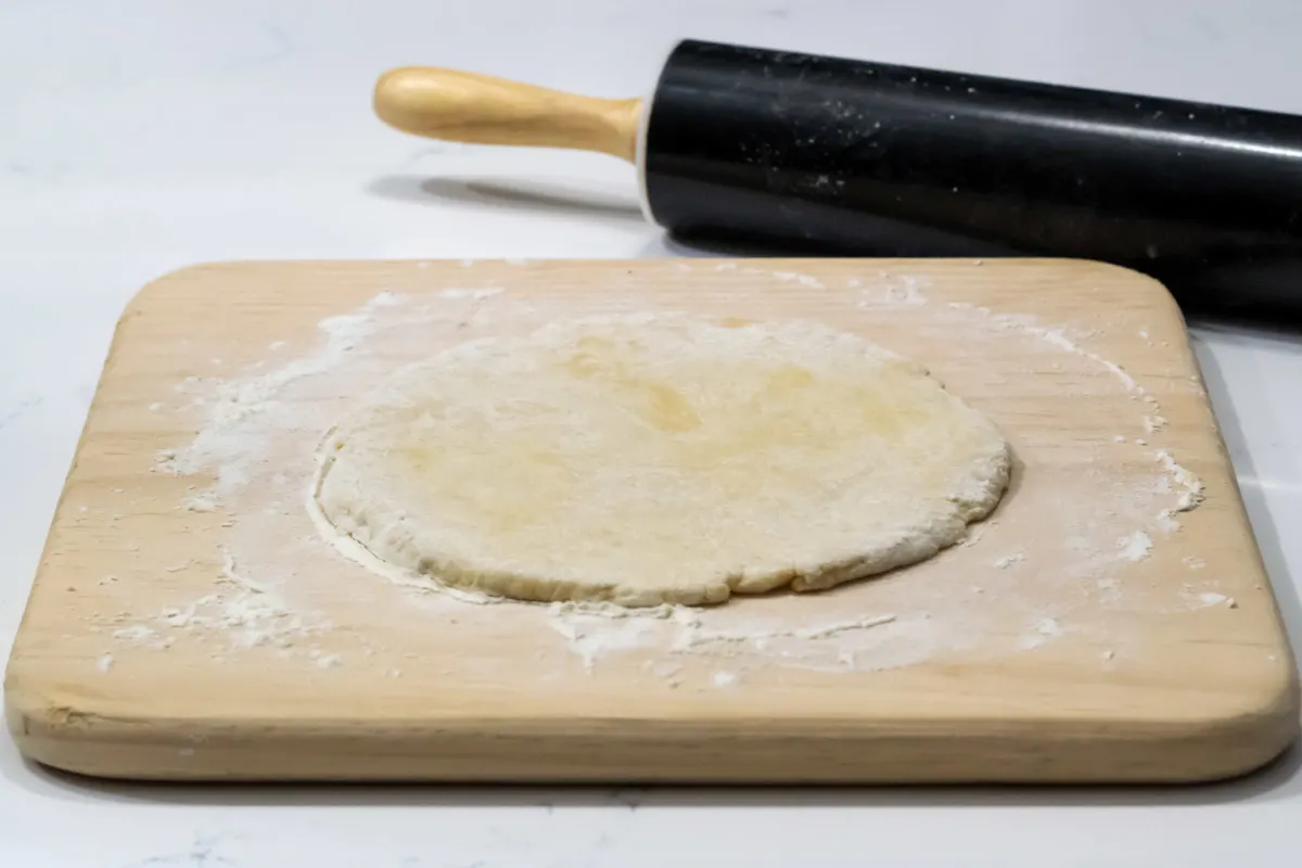 pizza dough rolled out onto a cutting board.