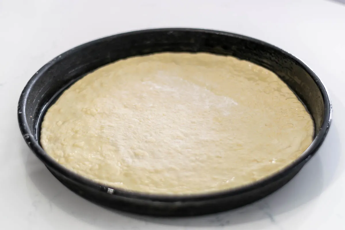 pizza dough placed into a pizza pan.