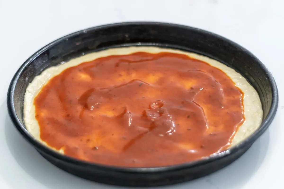 pizza sauce on top of pizza dough.