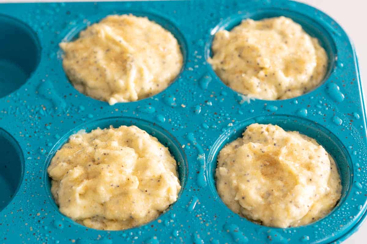 muffin batter topped with turbinado sugar in 4 cups of a muffin pan.