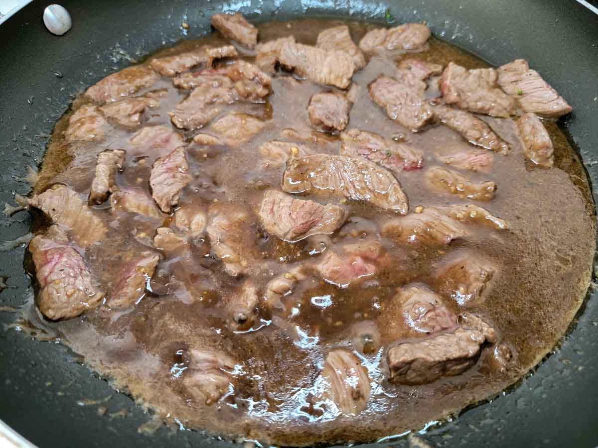 stir fry sauce added to beef in a skillet.