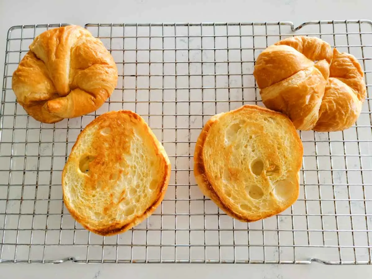 4 toasted croissant halves cooling on a wire rack.