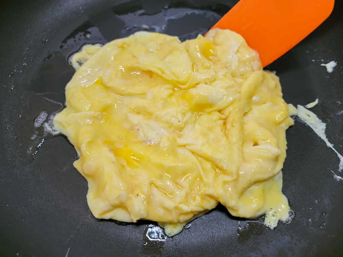 scrambled eggs cooking in a frying pan.