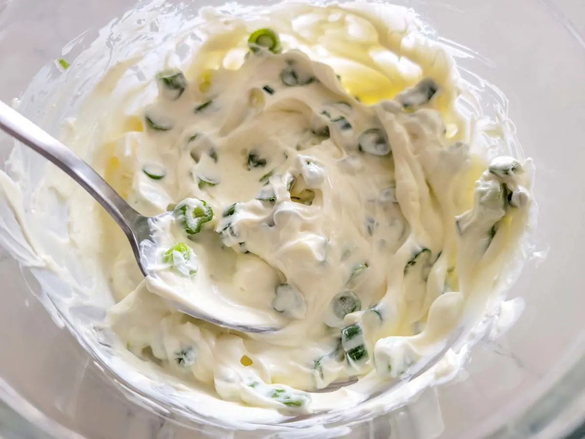 cream cheese mixed with green onions in a bowl.