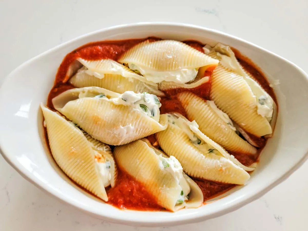 jumbo stuffed shells and spaghetti sauce in a casserole dish.