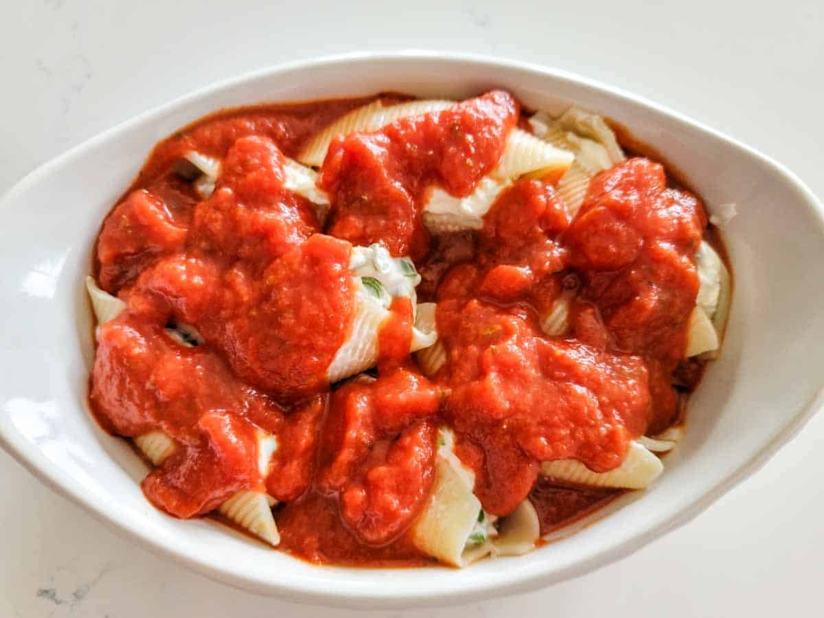 shells with cheese and spaghetti sauce in a casserole dish.