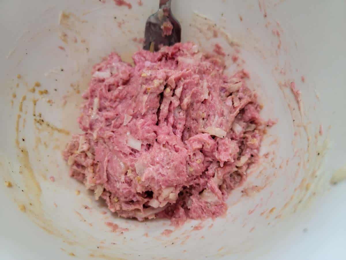 ground turkey mixed ith onion, garlic, mayo, worcestershire sauce, salt and pepper mixed in a bowl.