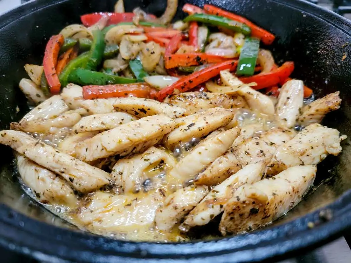chicken, green pepper, red pepper, and onions mixed with fajita seasonings in a cast iron skillet.