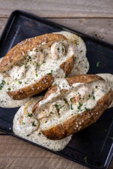 two shrimp stuffed potatoes on a baking sheet.