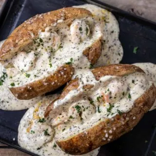 two shrimp stuffed potatoes on a baking sheet.