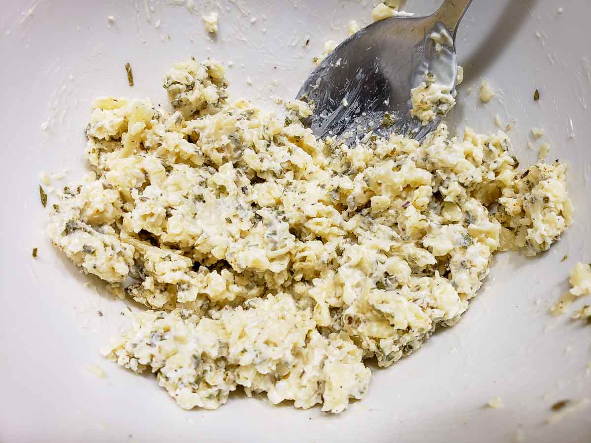 Parmesan cheese, butter, mayonnaise, chives, season salt, dried basil, and black pepper mixed in a bowl.