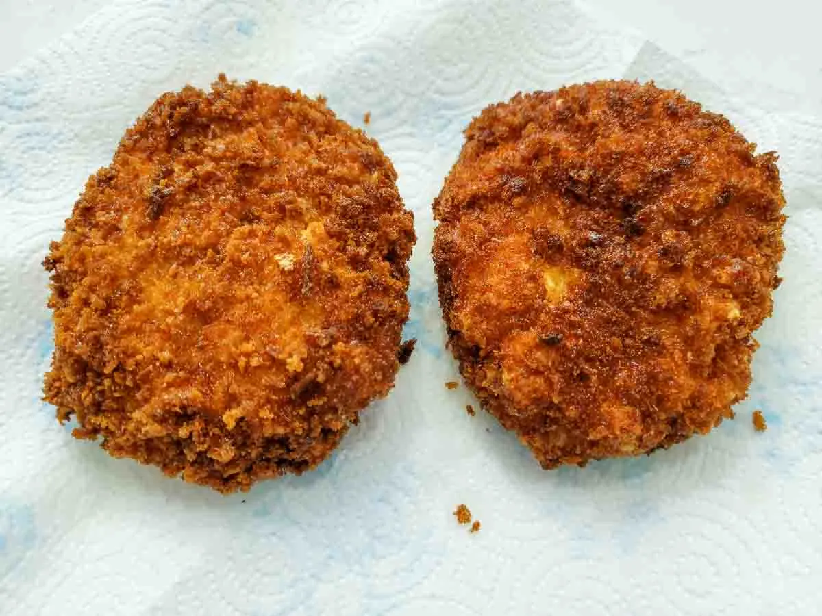 two fried shrimp patties draining on paper towel.