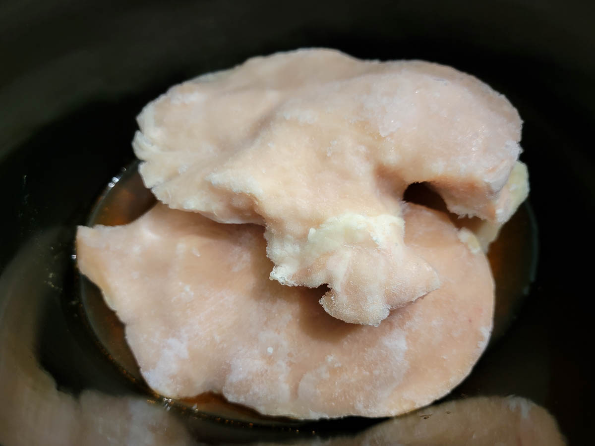 boneless chicken and taco seasoned broth in a slow cooker.