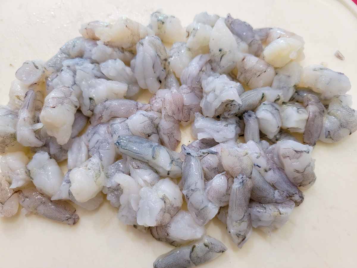 raw shrimp diced on a cutting board.