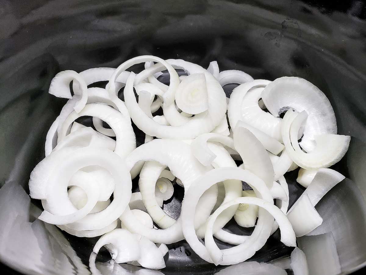 sliced onions in a crock pot.