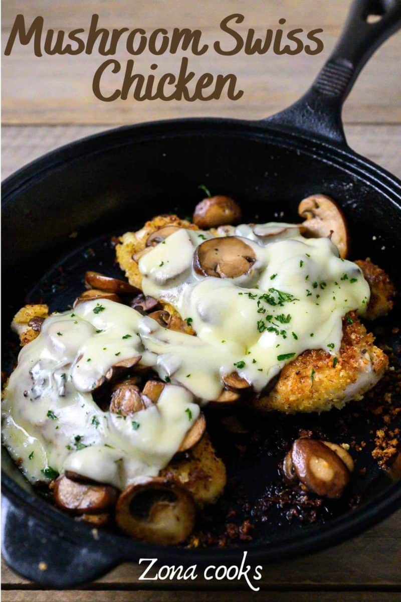 Smothered Cheesy Chicken with mushrooms in a cast iron skillet.