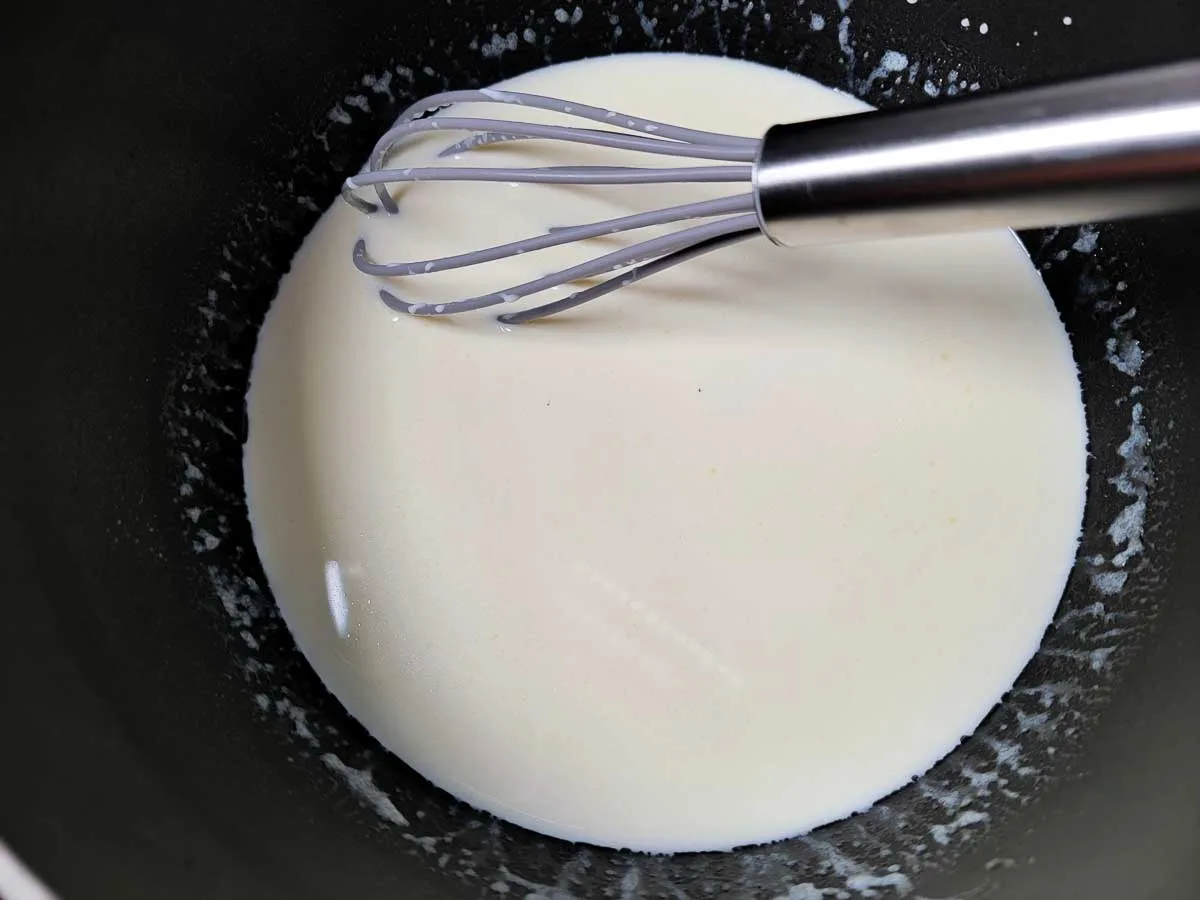 heavy cream whisked into flour mixture in a pan.