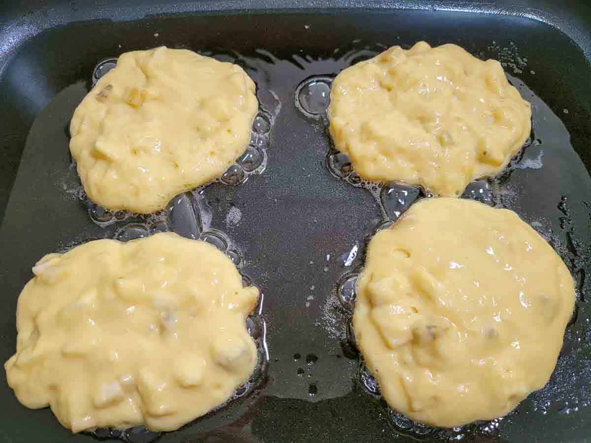 4 flapjackes cooking in an electric skillet.