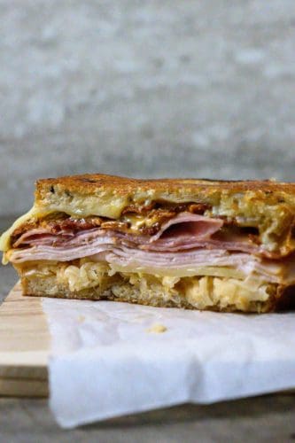Reuben Club Sandwich cut open on parchment paper.