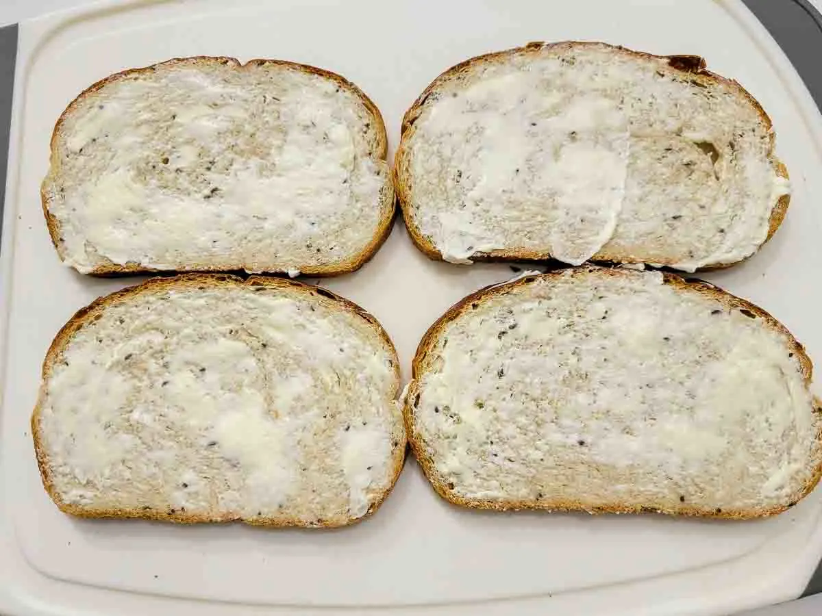 4 slices of rye bread spread with butter.