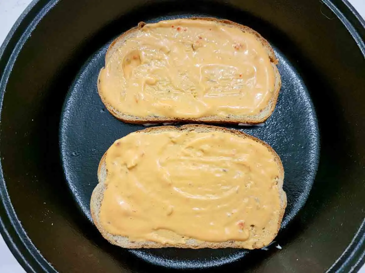 thousand island dressing on two slices of rye bread in a cast iron skillet.