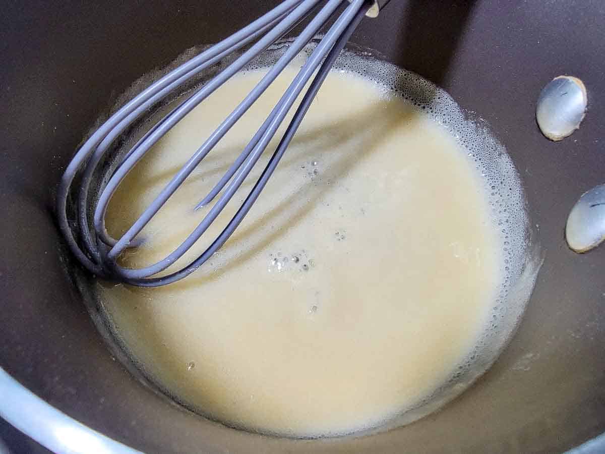 butter and flour roux cooking in a pan with a whisk.