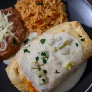 Shrimp Chimichanga on a plate with sides of spanish rice and refried beans.