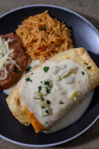 Shrimp Chimichanga on a plate with sides of spanish rice and refried beans.
