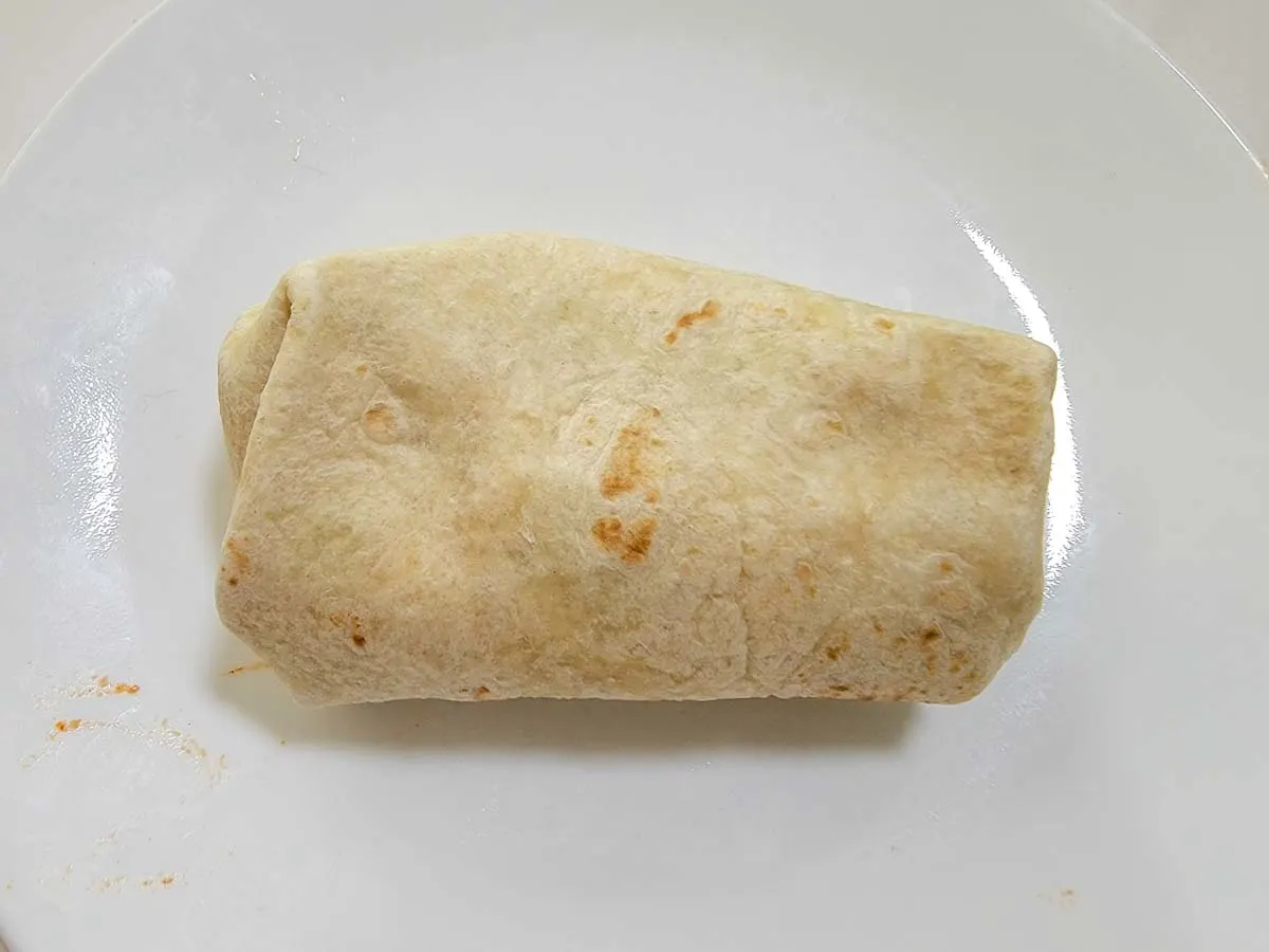 a chimichanga wrapped like an envelope on a plate.