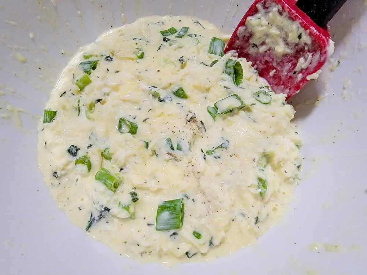 cheese, sour cream, green onions, beaten egg, basil, salt, and black pepper mixed in a bowl.