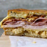 Reuben Club Sandwich cut open on parchment paper.