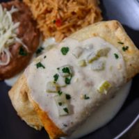 Shrimp Chimichanga on a plate with sides of spanish rice and refried beans.