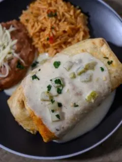 Shrimp Chimichanga on a plate with sides of spanish rice and refried beans.