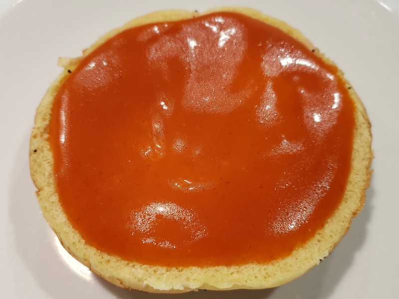 a sandwich bun bottom topped with red ranch sauce.