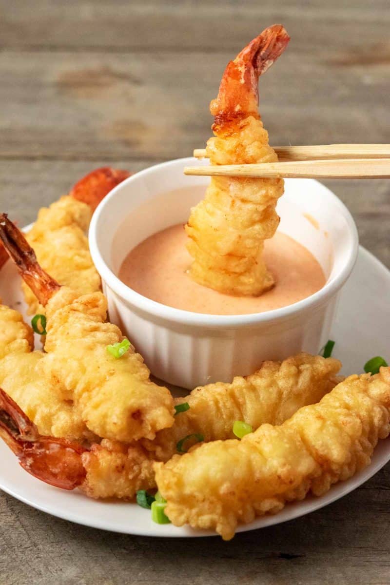 shrimp tempura being dipped into yum yum sauce.