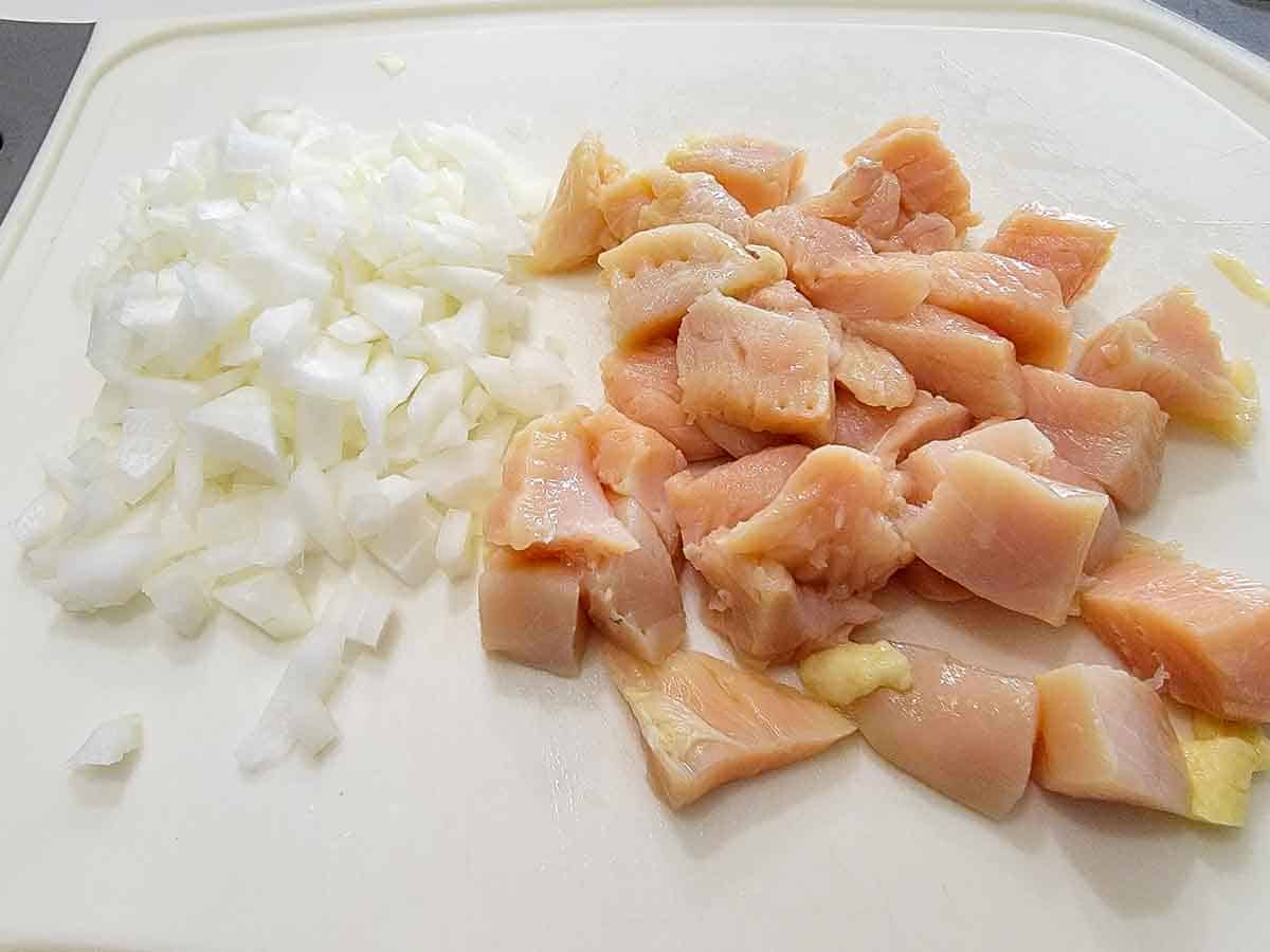 diced chicken and onions on a cutting board.