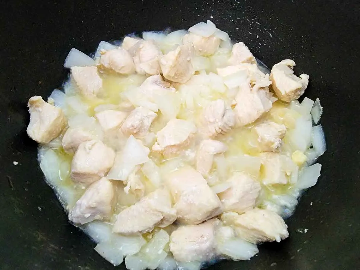 butter, onions, and chicken cooking in a pan.