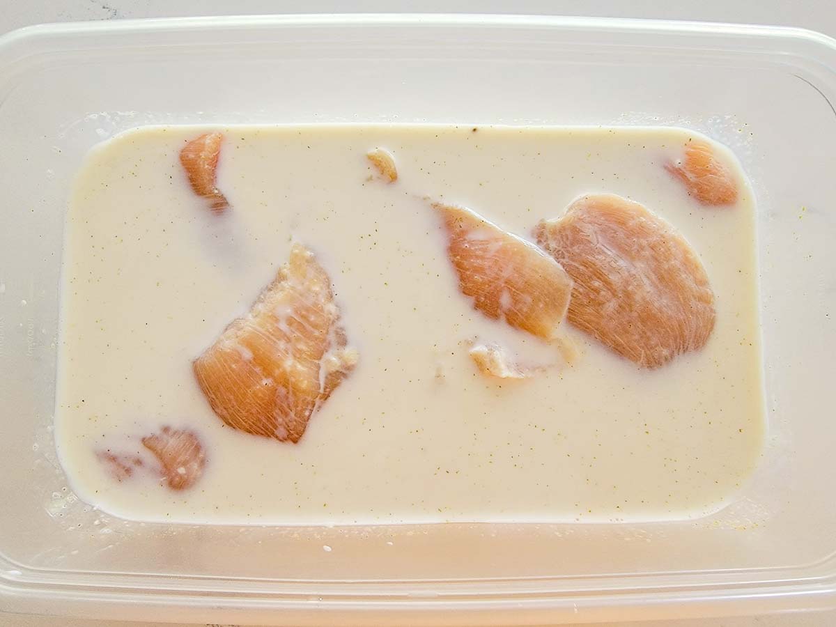 boneless chicken soaking in milk, vinegar, salt, and cumin.