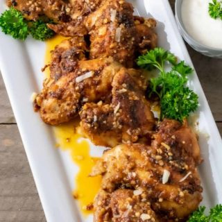 garlic parm chicken wings on a platter with a side of ranch dressing.