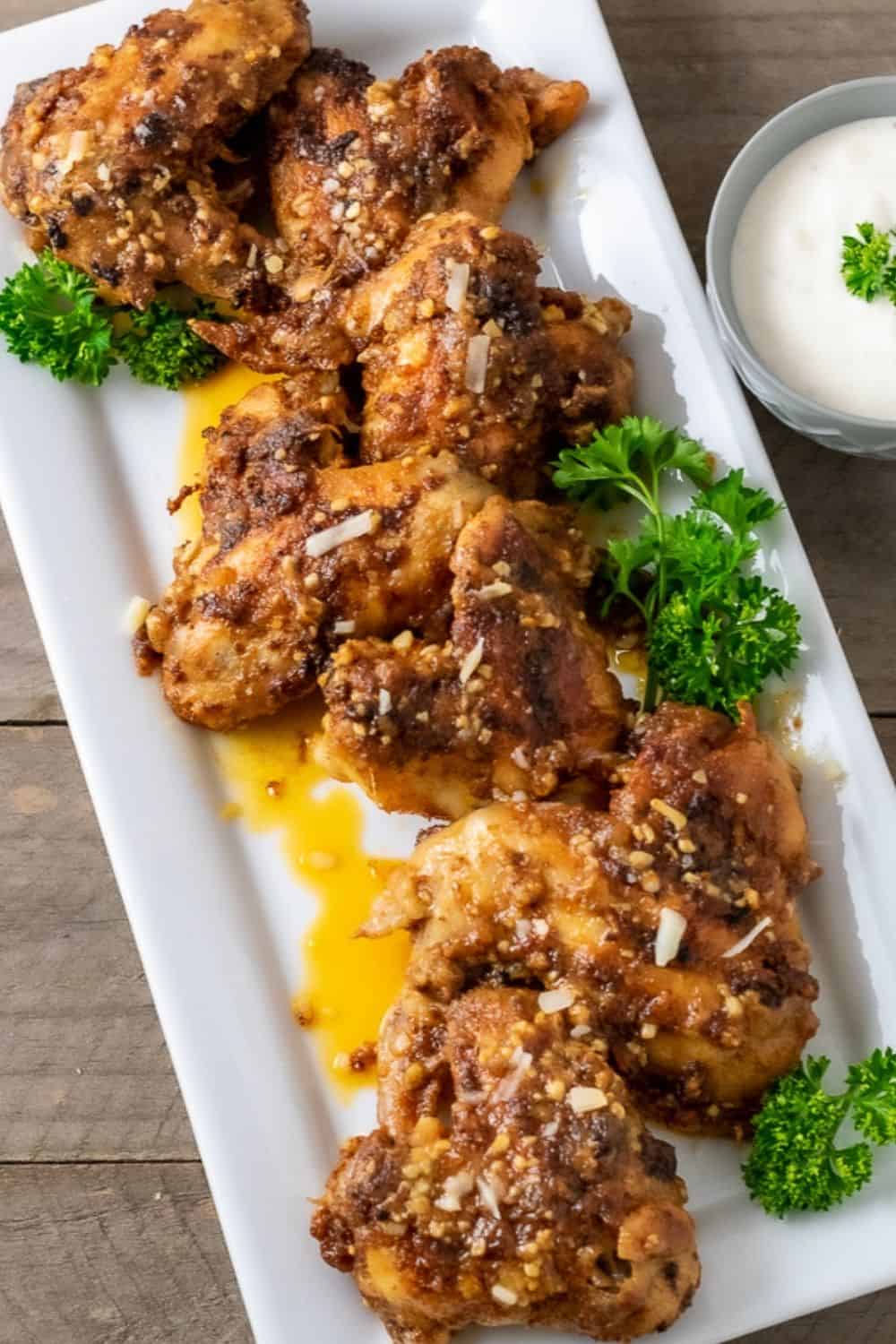 garlic parm chicken wings on a platter with a side of ranch dressing.