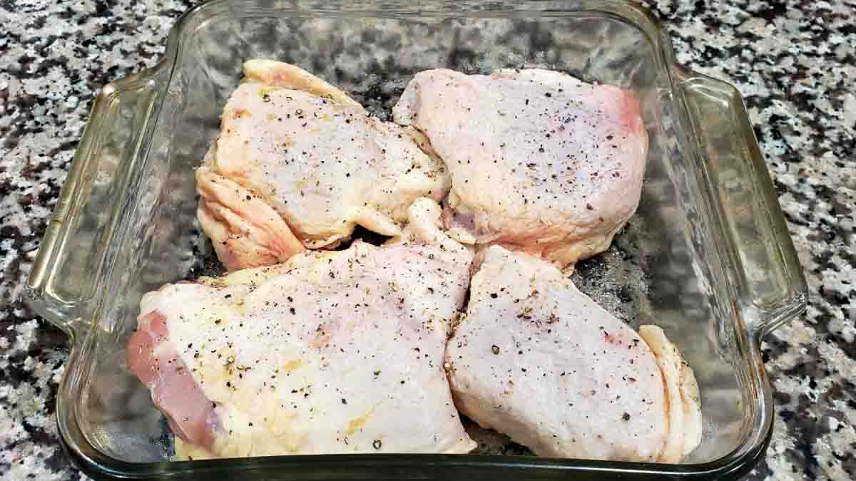 four raw thicken thighs in a baking dish.