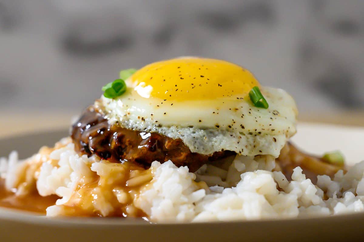 Easy Loco Moco with white rice topped with a beef patty, topped with brown gravy, topped with an egg on a plate.